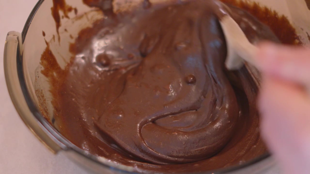 Mescolando l'impasto morbido per torta brownie al cioccolato in una ciotola di vetro