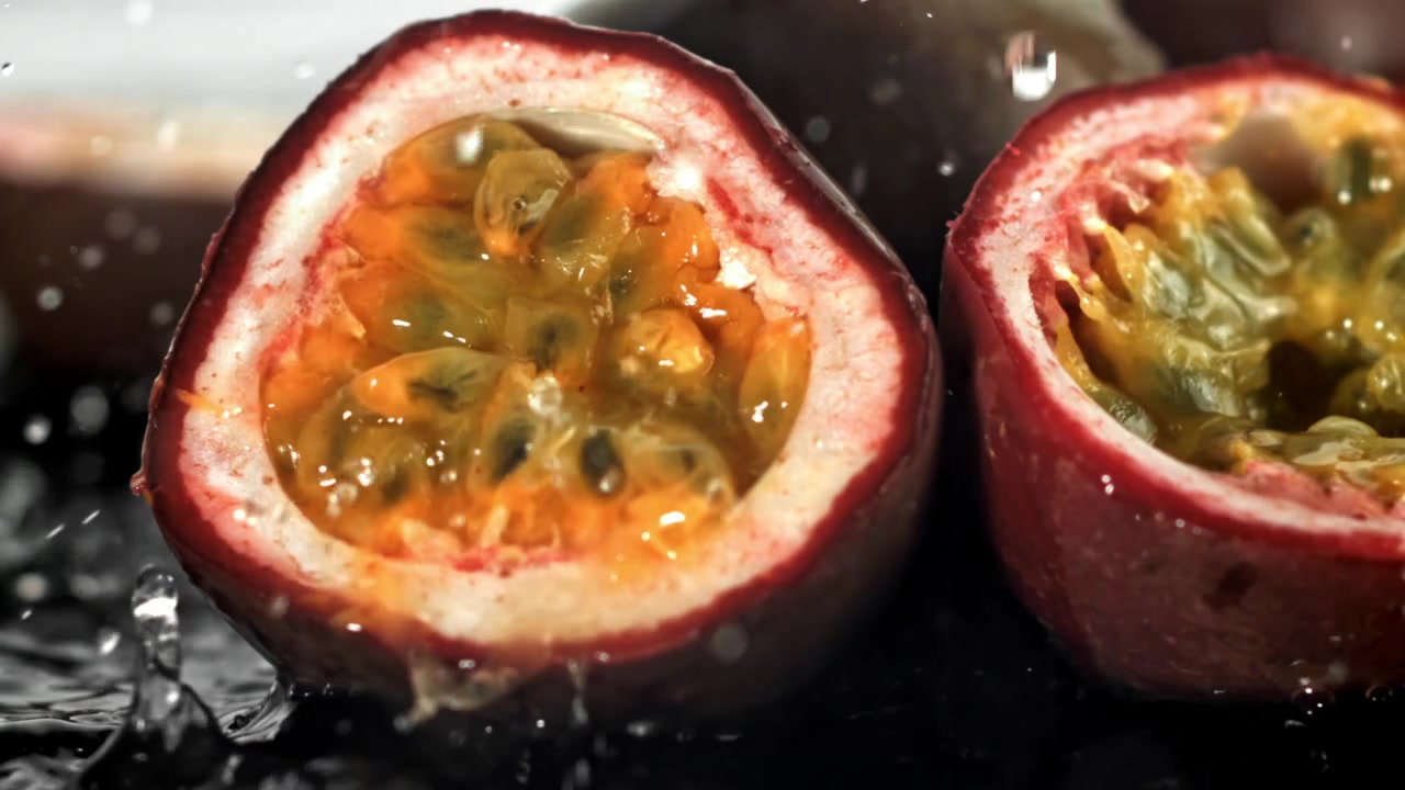 Slowmotion af vand, der plasker på friskudskåret passionsfrugt