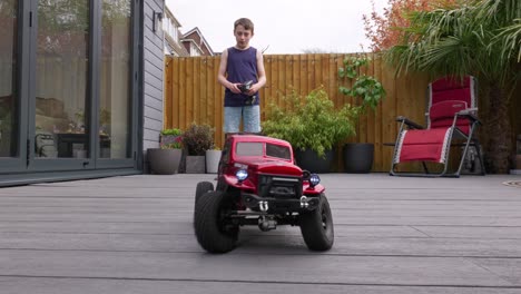 young boy at home outdoors in the garden playing with his rc car, truck, 4 x 4