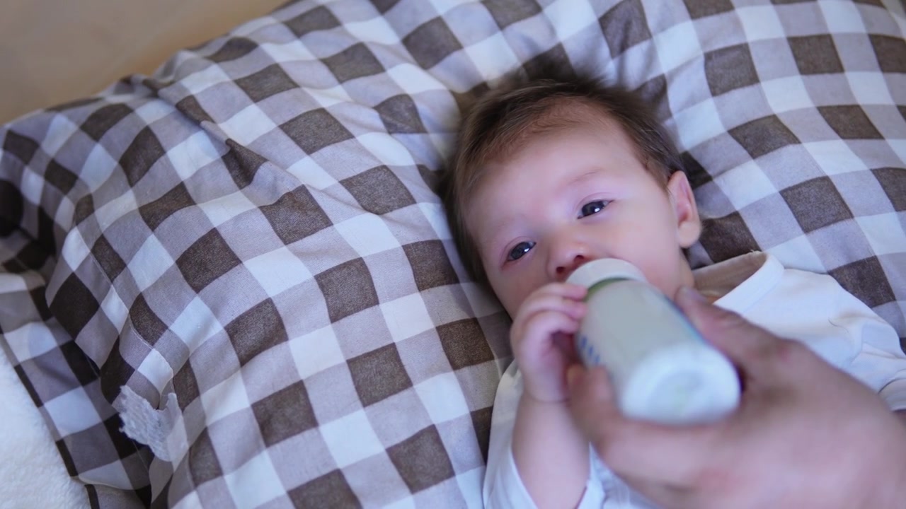 Un bambino piccolo che beve dal suo biberon.