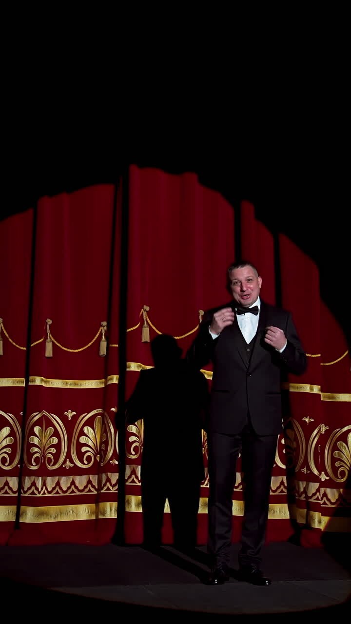 Announcer on a stage in theater. Bright round light on one person. man in black suit performs to the auditorium. Vertical video