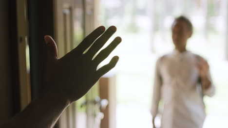 close up of dad waving to his son who standing at house entrance in blurred background and then closing the door