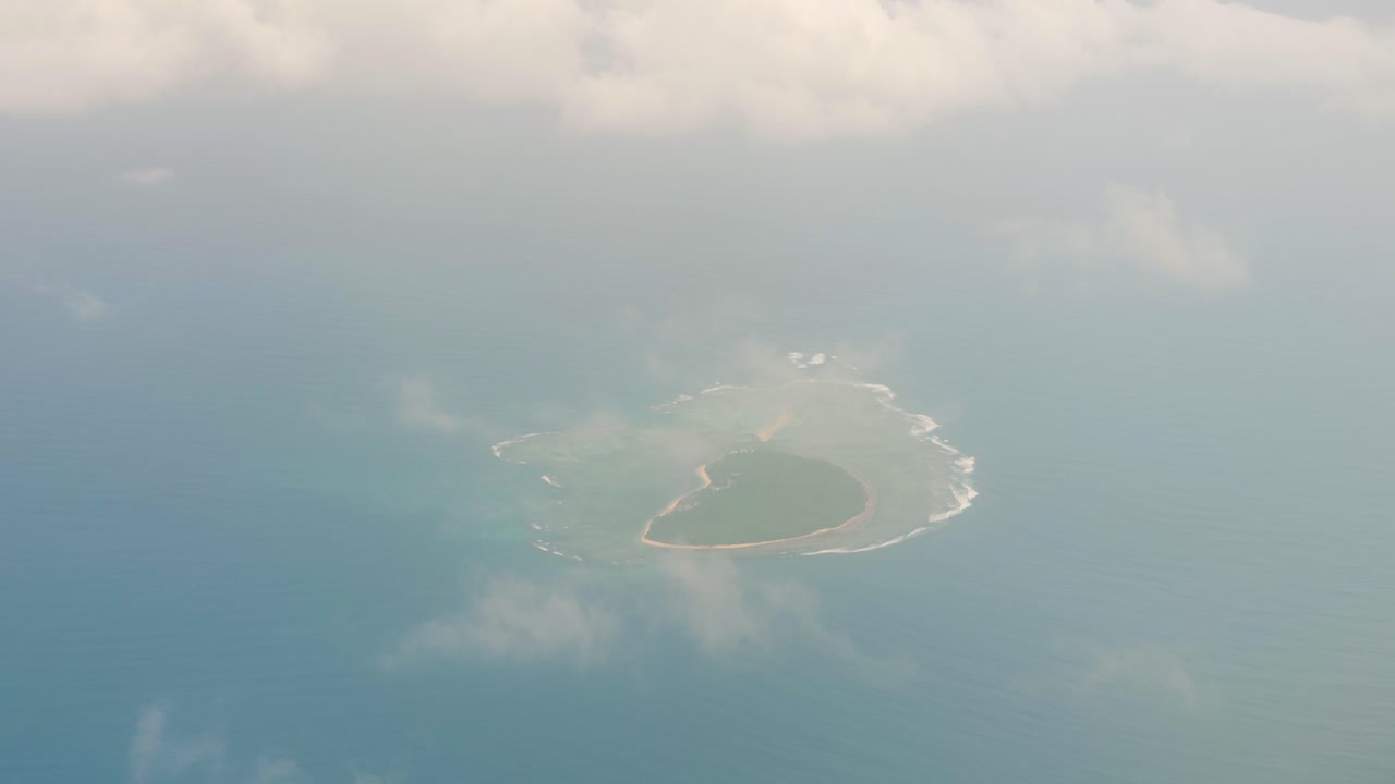 사람이 살지 않는 열대 섬과 작은 구름이 보이는 비행기 창에서 조감도