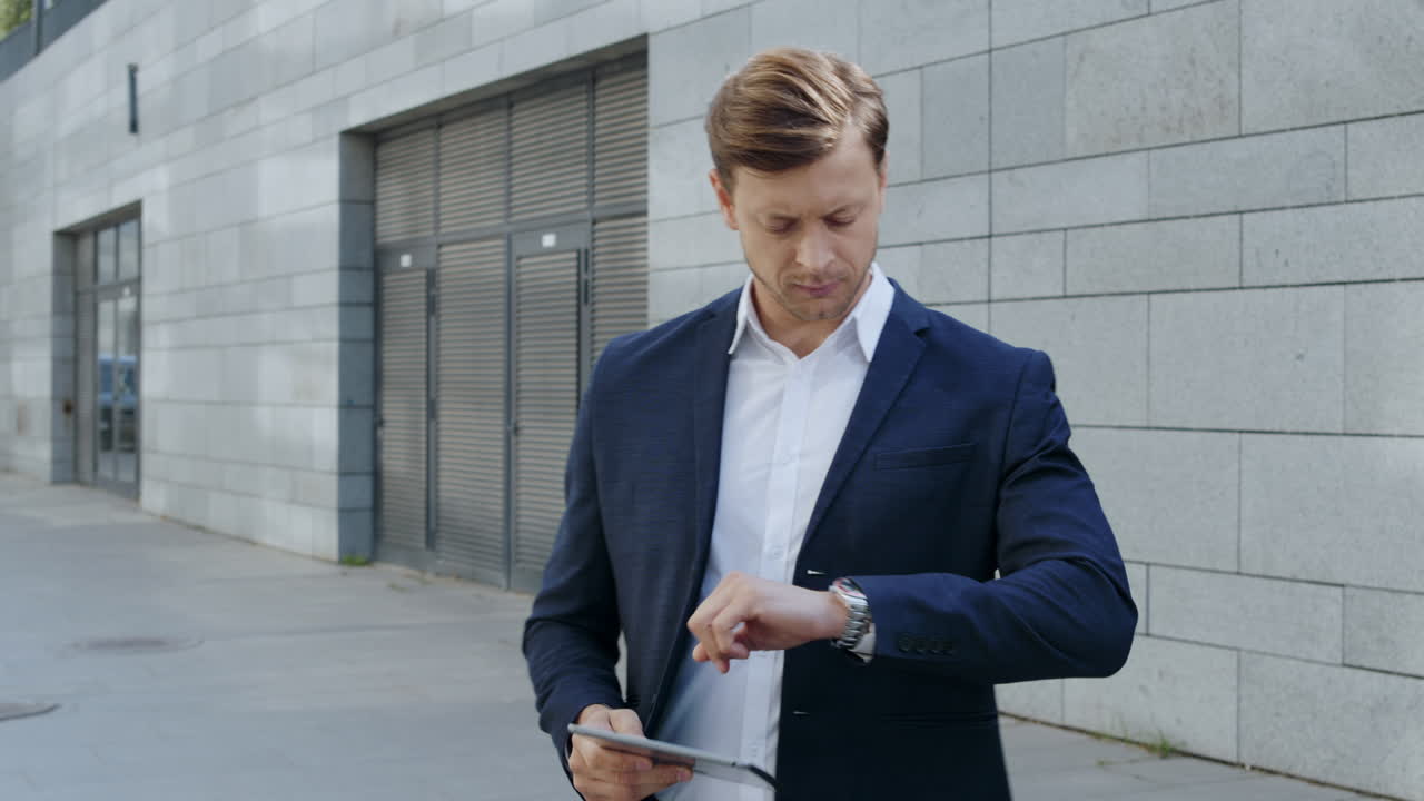 Businessman working on tablet at street. Manager waiting for partner on street