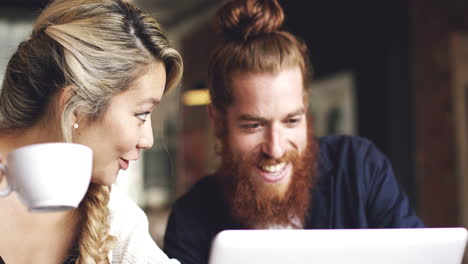 Young-couple-using-digital-tablet-computer-in-cafe