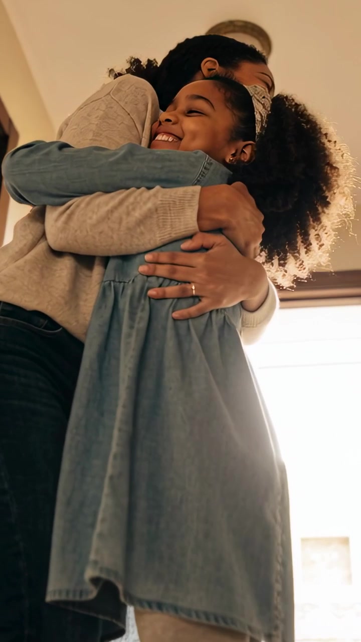 Video verticale: Mamma e figlia che si abbracciano nell'atrio, salutandosi, indossando maglione, vestito e anello.
