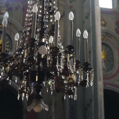 a luxurious chandelier hangs in the middle of a catholic cathedral on the background of frescoes. camera motion to the side