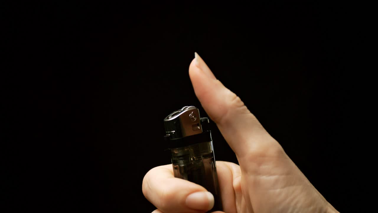 느린 움직임의 불꽃: 손이 불꽃을 켜고 엄지손가락이 불꽃과 불꽃의 매혹적인 전시에서 그것을 활성화하는 것을 지켜보십시오.