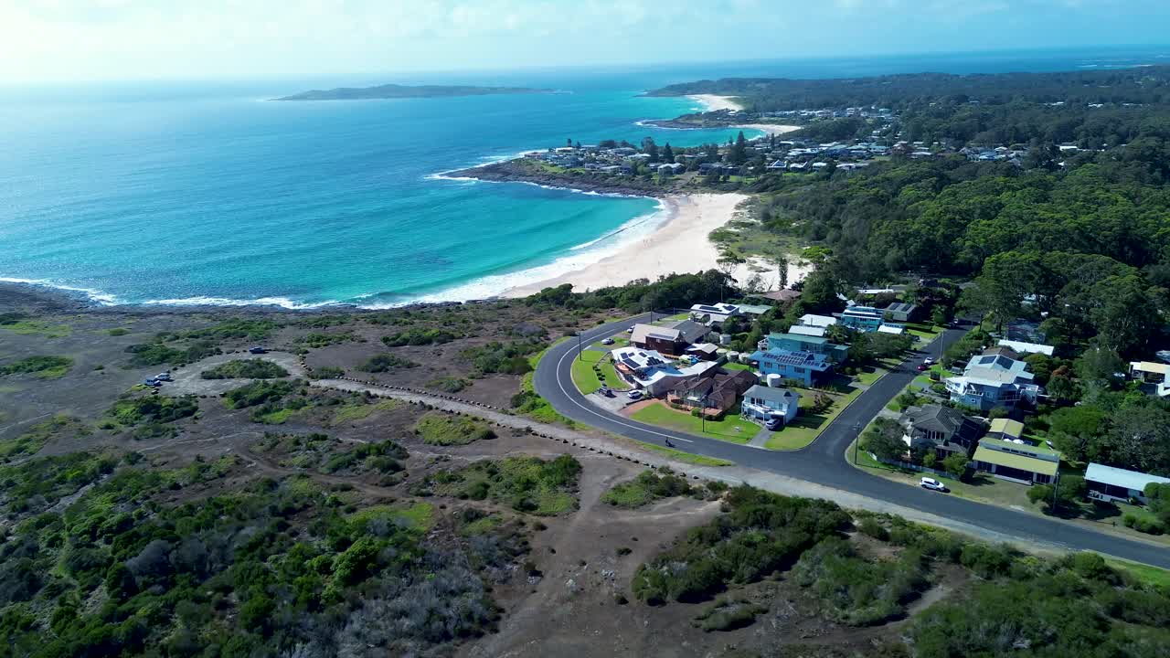 Drone aerial landscape of Cormorant Beach residential housing roads street with sandy bay bushland forest rocky reef Bawley Point Shoalhaven Australia travel tourism