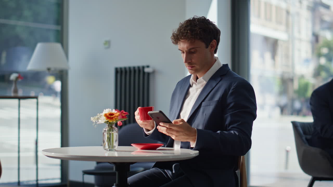 Relaxed man sitting cafeteria table with cappuccino. Manager receiving message