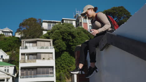 Slow-motion-shot-of-a-woman-sitting-resting-on-a-wall-and-walking-away