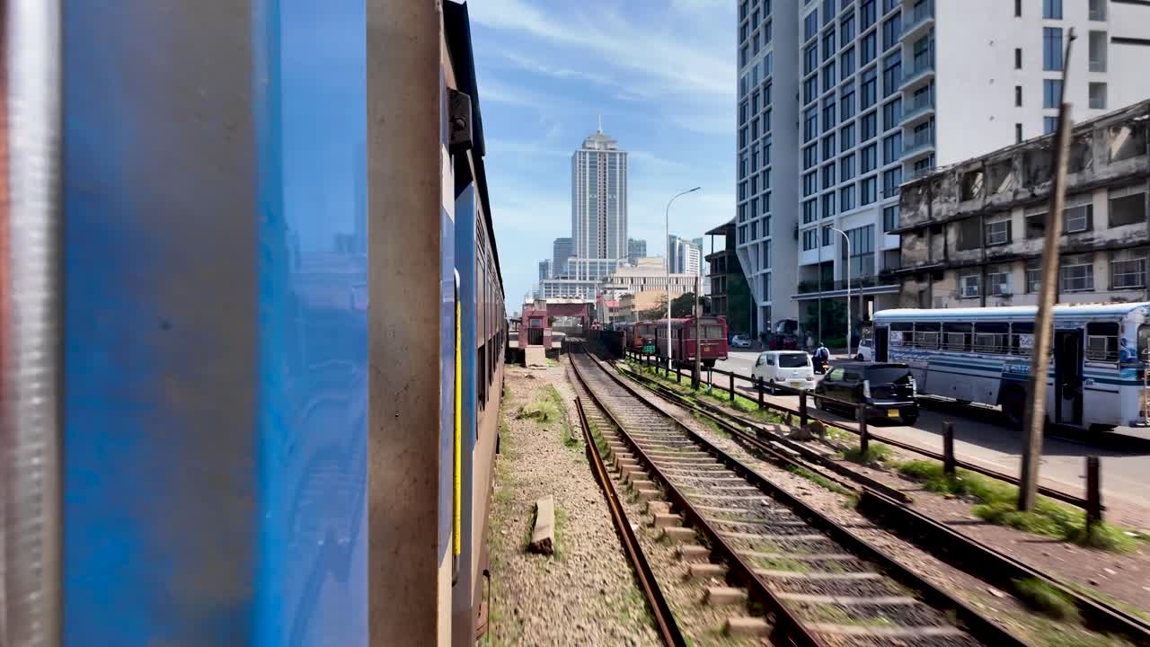 Pov from open train door, travelling beside roadside, showing cityscape of colombo, sri lanka