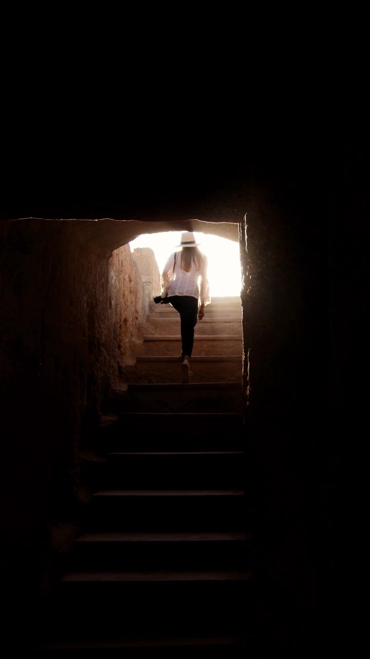 A person ascends a staircase towards a bright light creating a sense of hope and journey