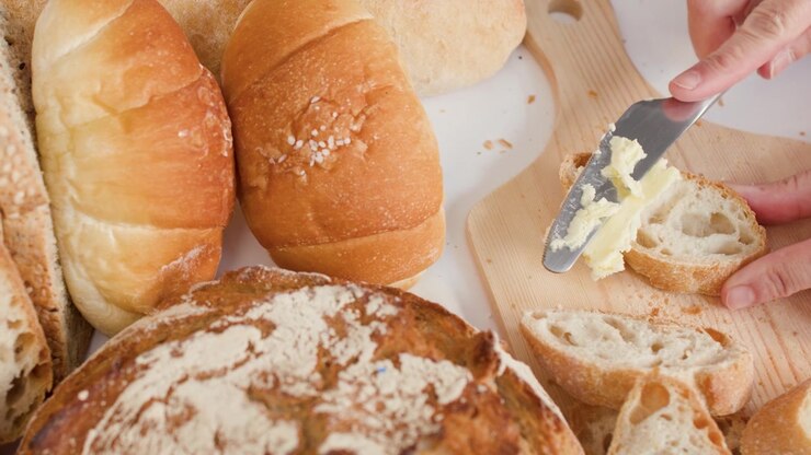 Close-up shot of butter spreading on crusty bread surrounded by sourdough and French loaves.