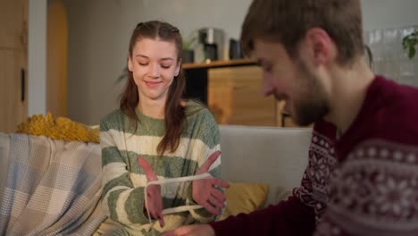 couple playing a string game on a couch