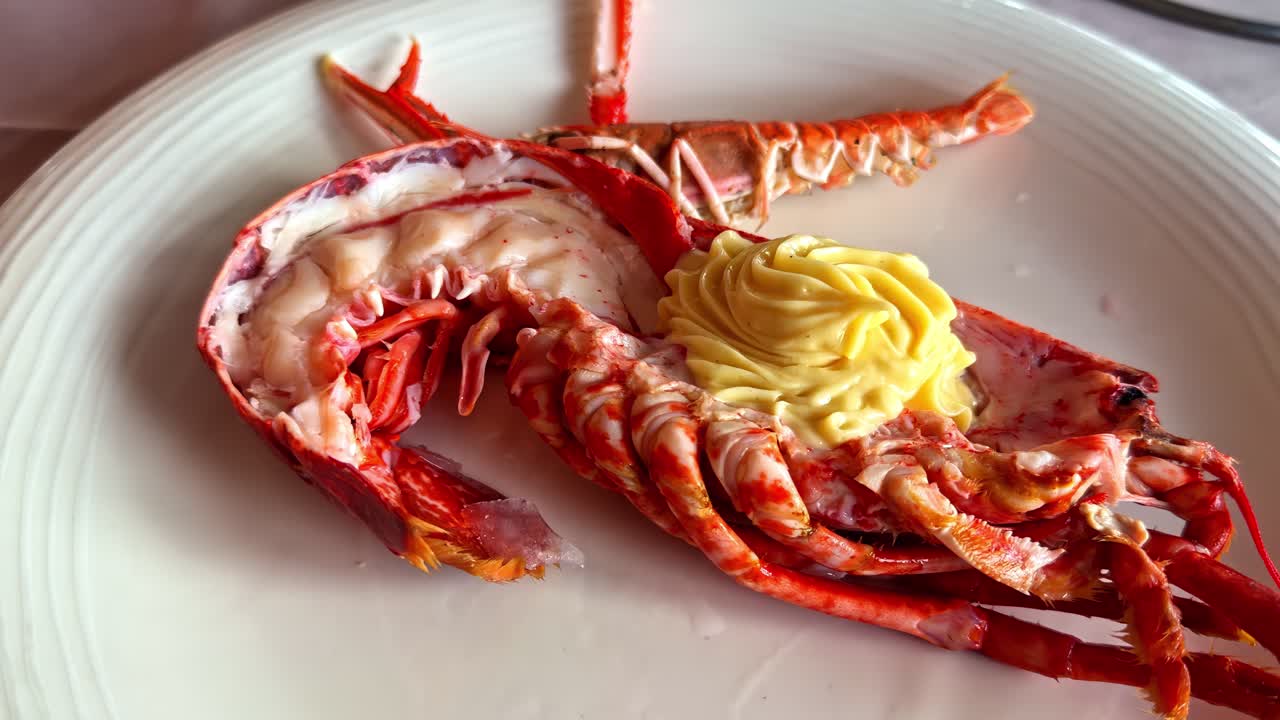 Aragosta cotta con salsa al burro servita su un piatto bianco, pronta per il consumo