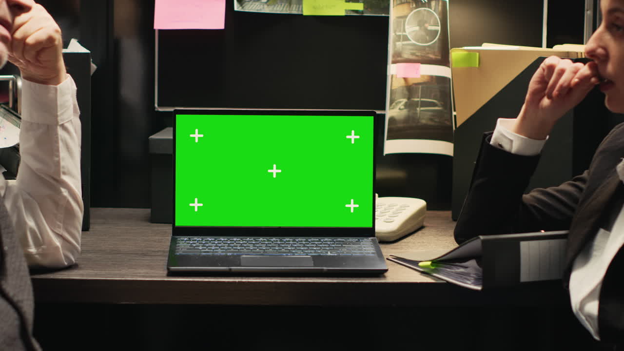 Detectives working on a case with a green screen laptop
