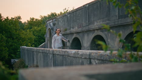 tranquil model walking medieval palace balcony touching stone wall at evening.