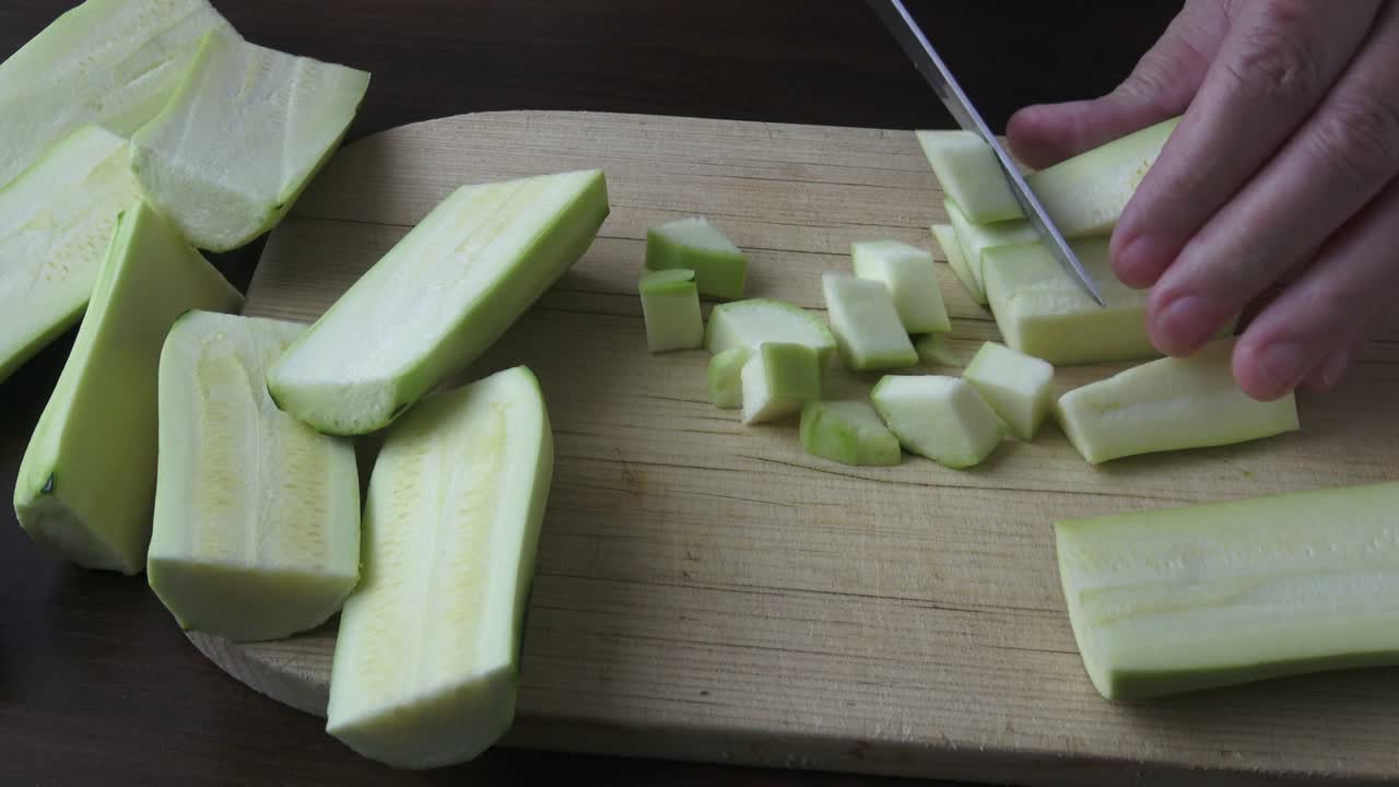 Woman holding kitchen knife, chopping peeled zucchini. Healthy eating concept.