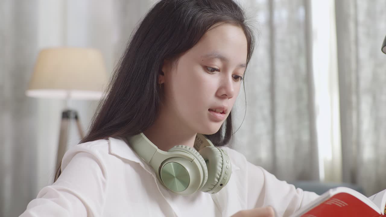 십대 소녀 가 헤드폰 을 착용 하여 공부 하고 있다