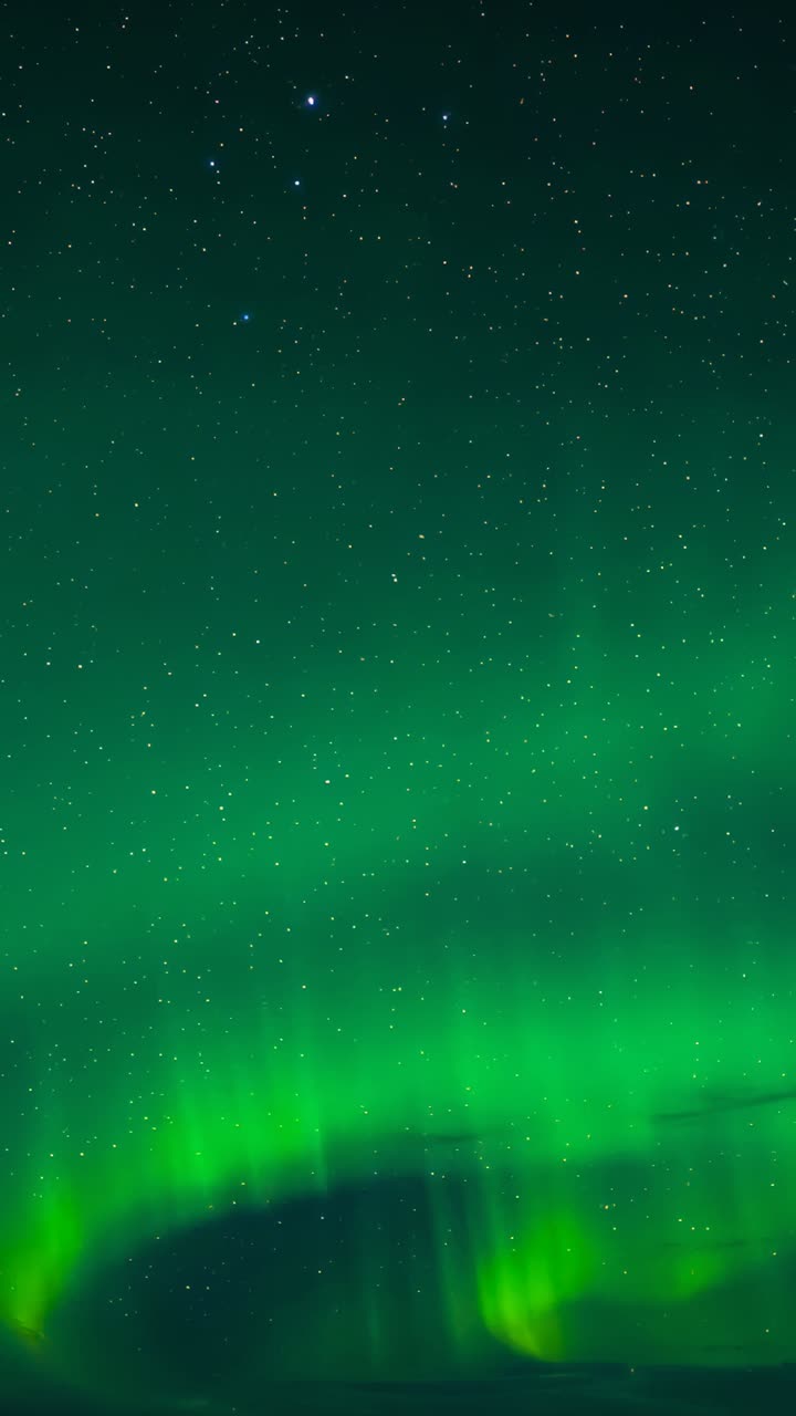 Vertical video: Shimmering auroral bands responding to solar wind, drifting across polar star field