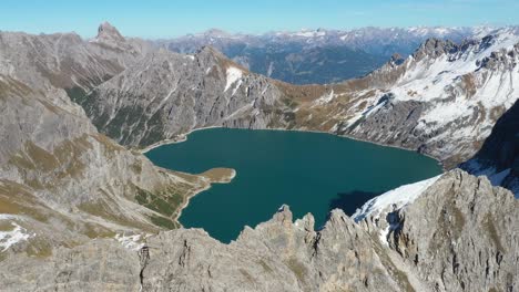 Drone-shot-moving-upwards-and-tilting-down-of-the-colorful-and-heart-shaped-Love-Heart-Lake-in-Lunersee,-Switzerland