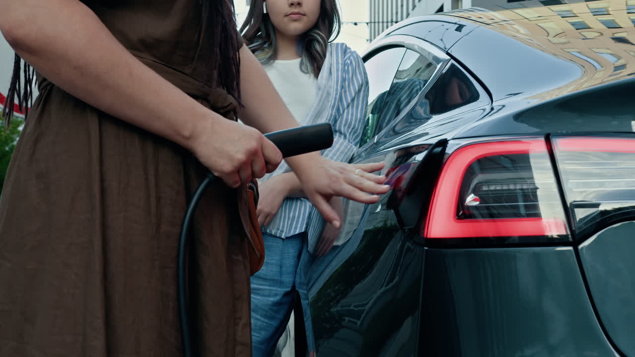 mujer y niña cargando un coche eléctrico