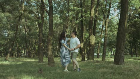 una feliz pareja embarazada y enamorada bailando en la naturaleza