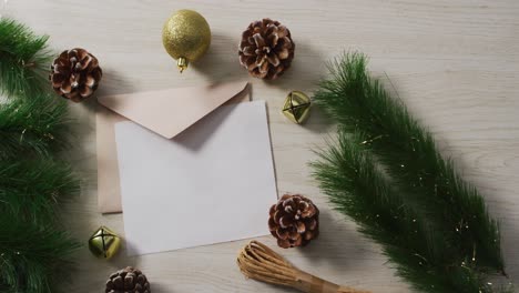 Animation-of-christmas-decorations-with-white-card-on-wooden-background