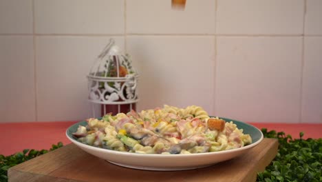 agregando picatostes a una pasta de ensalada en cámara lenta mujer cocinando a mano