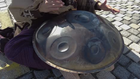 a street performer playing a hand pan instrument, also known as hang