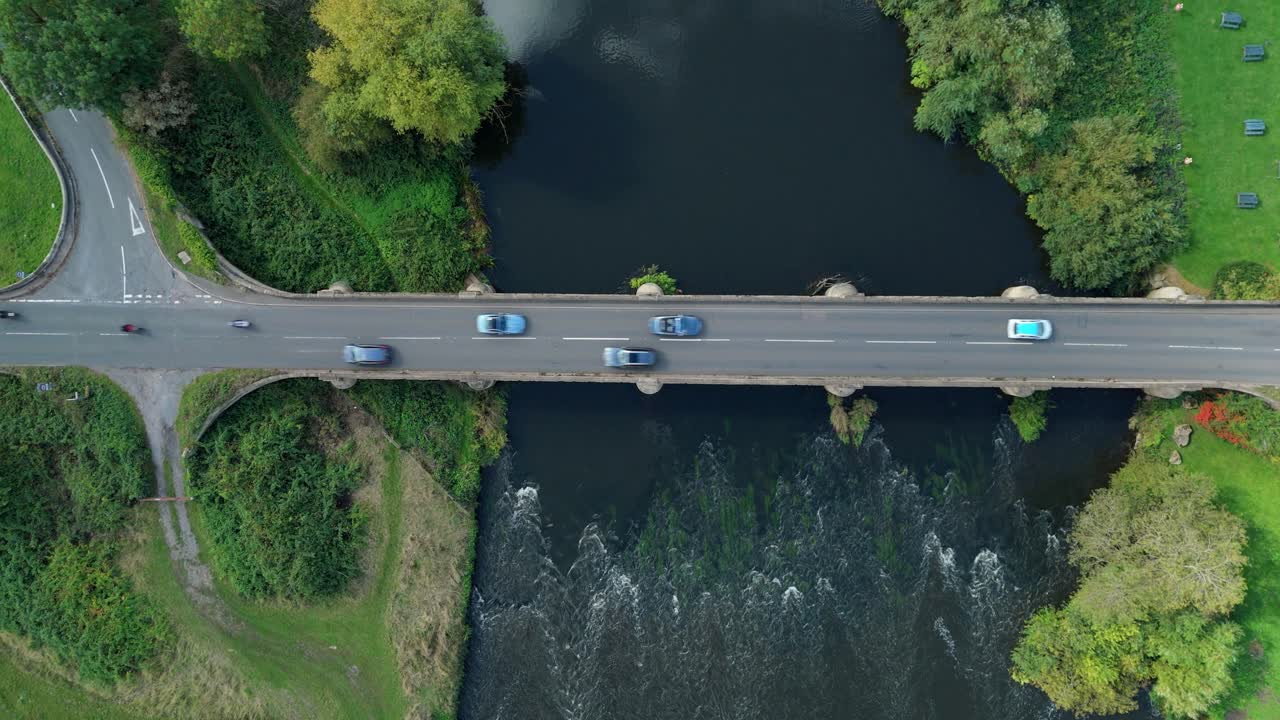 - High altitude drone sweep over river bridge and saltmarsh fringes showing cars on coastal road near Swarkstone UK