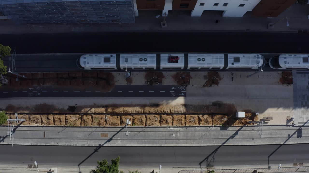 대중교통 트램이 자전거 도로를 타고 도시에서 자동차를 운전하고, 위에서 내려다 보입니다.