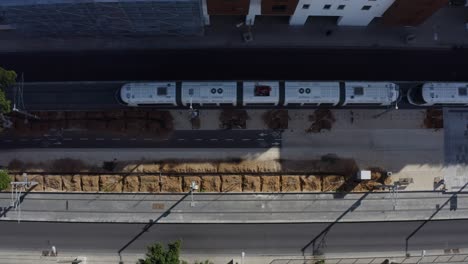 Public-transportation-tram-driving-by-cycling-lane-and-cars-in-the-city,-top-down-aerial-view