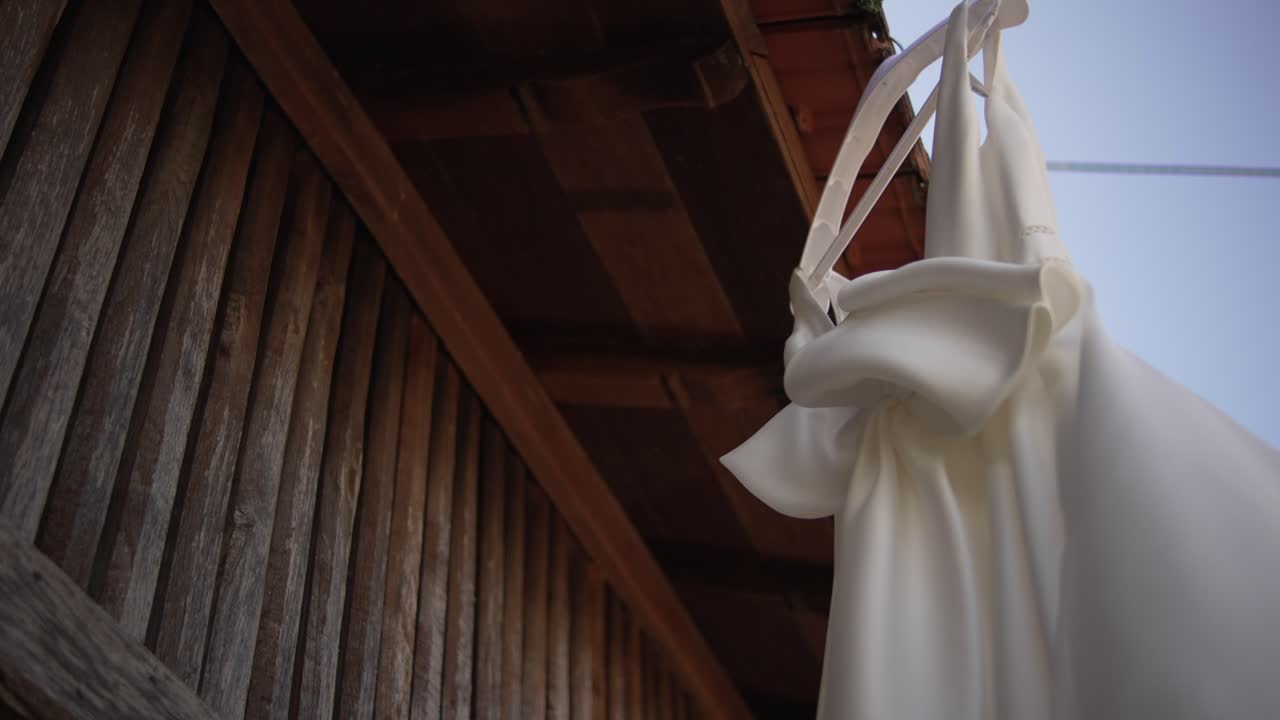 Vestido de novia blanco colgado al aire libre en un entorno rústico
