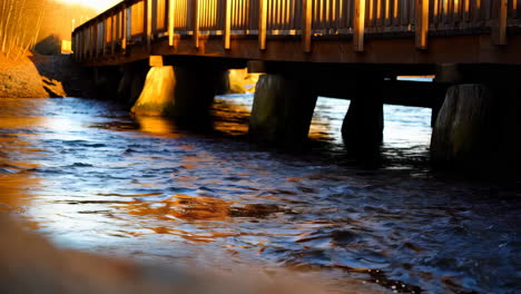 golden hour reflections under a wooden bridge