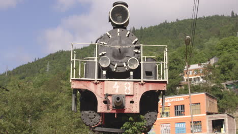 retro kukushka train exhibit with forest mountain at background in borjomi-bakuriani, georgia