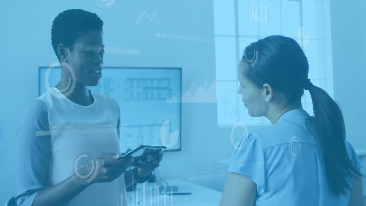 Animation of data processing over two diverse women discussing over a digital tablet at office
