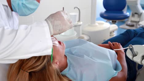 Dentist-examining-a-woman-teeth-in-the-dentists-chair