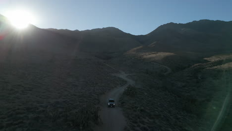 a drone follows a truck down a sandy desert road in the eastern sierra nevada mountain range at sunset