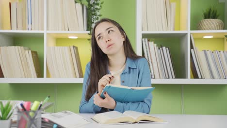 asian teenage girl doing research, thinking, taking notes.