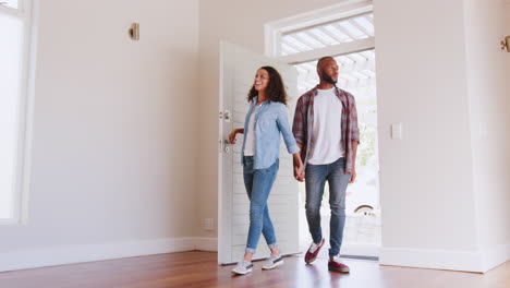 Toma-En-Cámara-Lenta-De-Una-Pareja-Abriendo-La-Puerta-Y-Caminando-En-El-Salón-Vacío-De-Una-Nueva-Casa