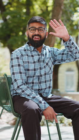 indian man smiling friendly at camera waving hands hello hi greeting or goodbye in city street