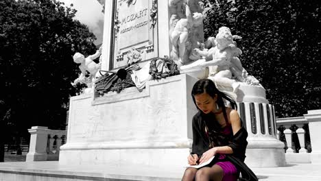 Mujer-Vestida-De-Púrpura-Leyendo-La-Estatua-De-Wolfgang-Amadeus-Mozart-En-Burggarten,-Viena,-Técnica-De-Color-Selectiva