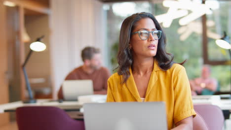 Mature-Businesswoman-Wearing-Glasses-Working-In-Office-On-Laptop-At-Desk