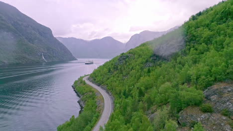 drone flying over panoramic road along green mountains of nordic fjord during summer season, norway