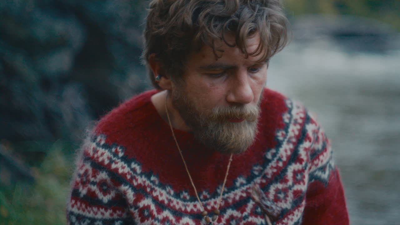 Man Eating Roasted Meat during Campsite Dinner by Flowing River