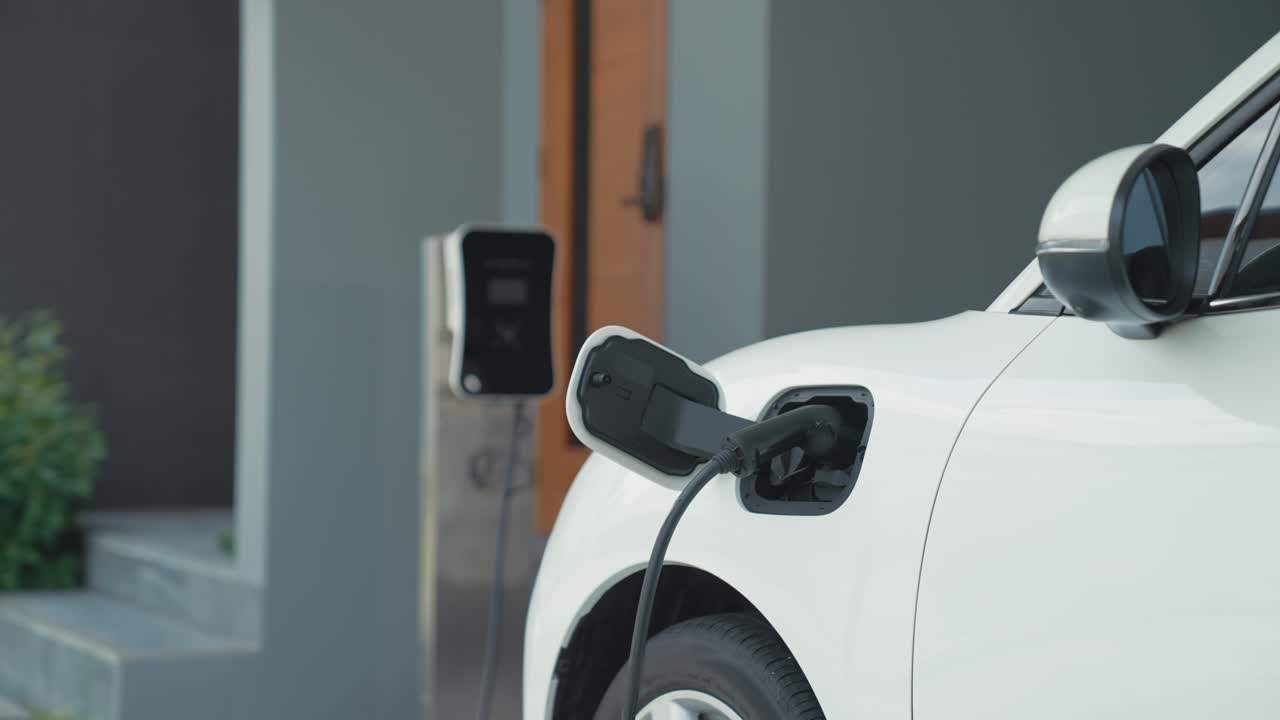 Progressive man unplugs the electric vehicle's charger at his residence.