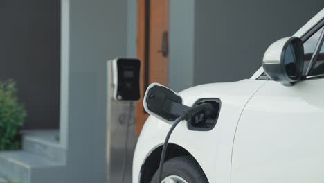 un hombre progresista desconecta el cargador del vehículo eléctrico en su residencia.