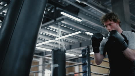 Agitated-fighter-working-on-blows-in-fitness-center.-Sportsman-training-kicks